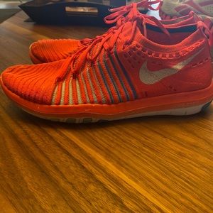 Women’s Nike free running shoe. Size 7.5. Bright red collar with blue stripes.